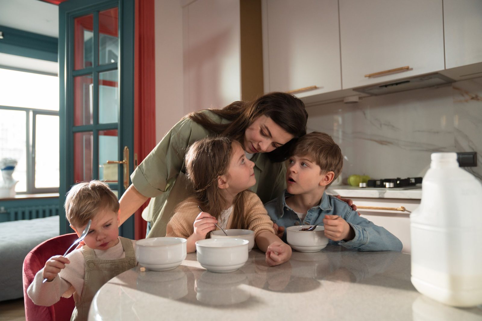 Uma mãe e os seus três filhos a tomar o pequeno-almoço na cozinha de uma casa de troca